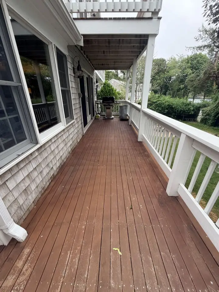 Long wood deck with railing along a Cape Cod home