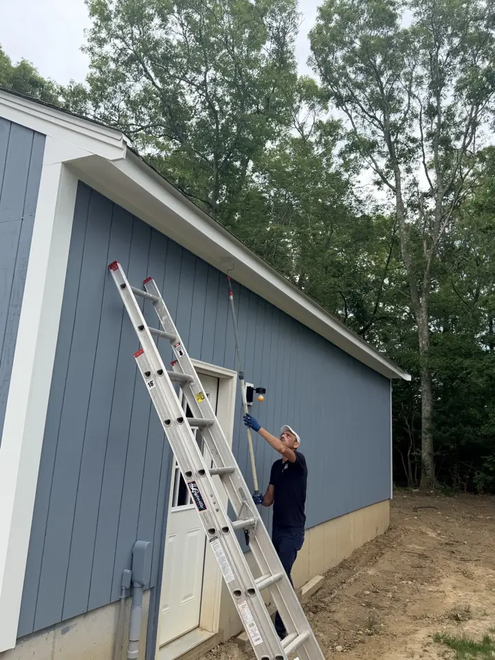 Crew member painting a garage from a ladder
