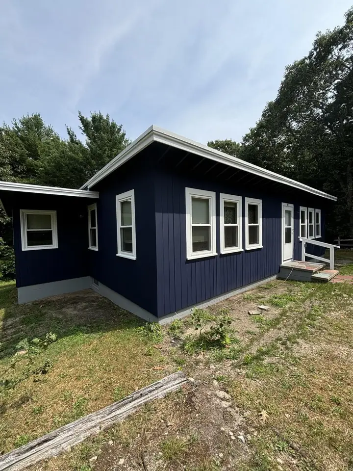 Blue house with new white trim after wood replacement and painting