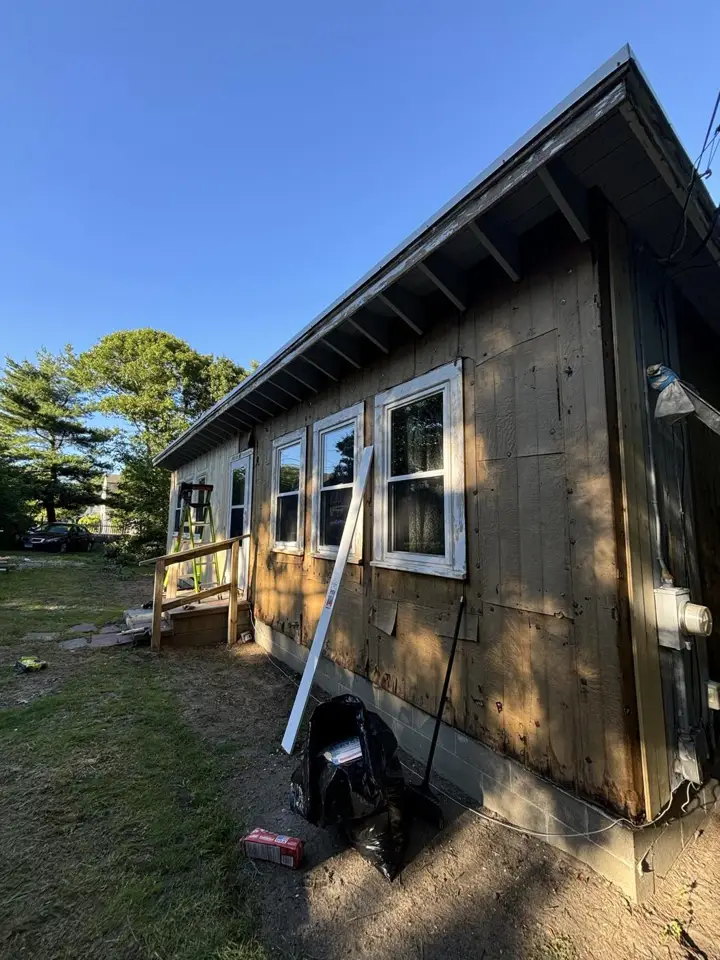 Blue house with rotted siding being repaired before painting