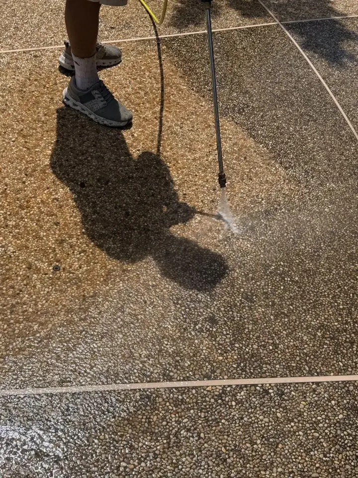 Pressure washer cleaning a pebble driveway surface