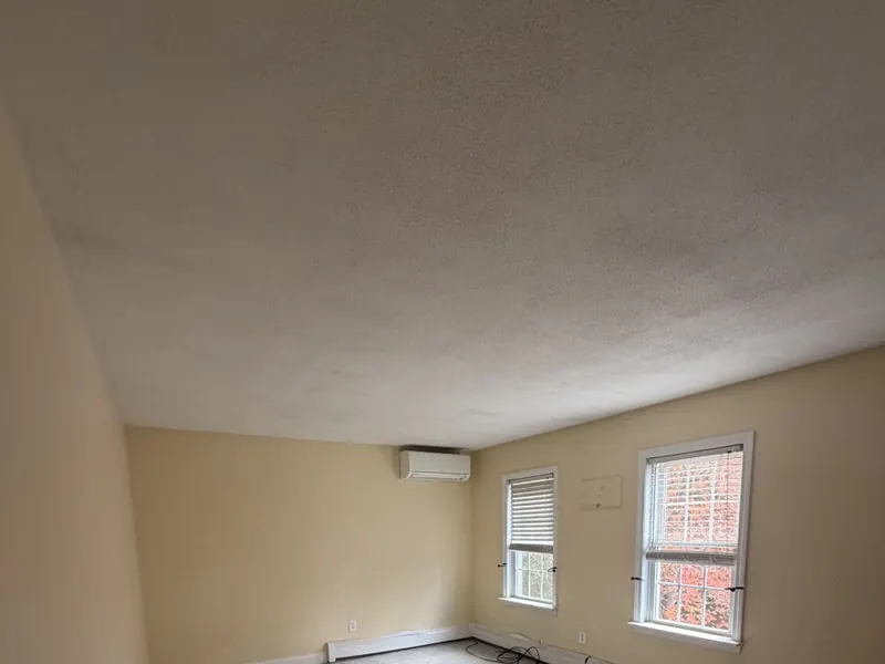 Textured popcorn ceiling in a bedroom before painting