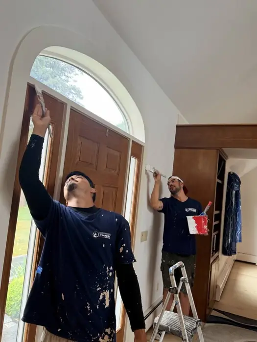 Two painters at work on an entry door and trim