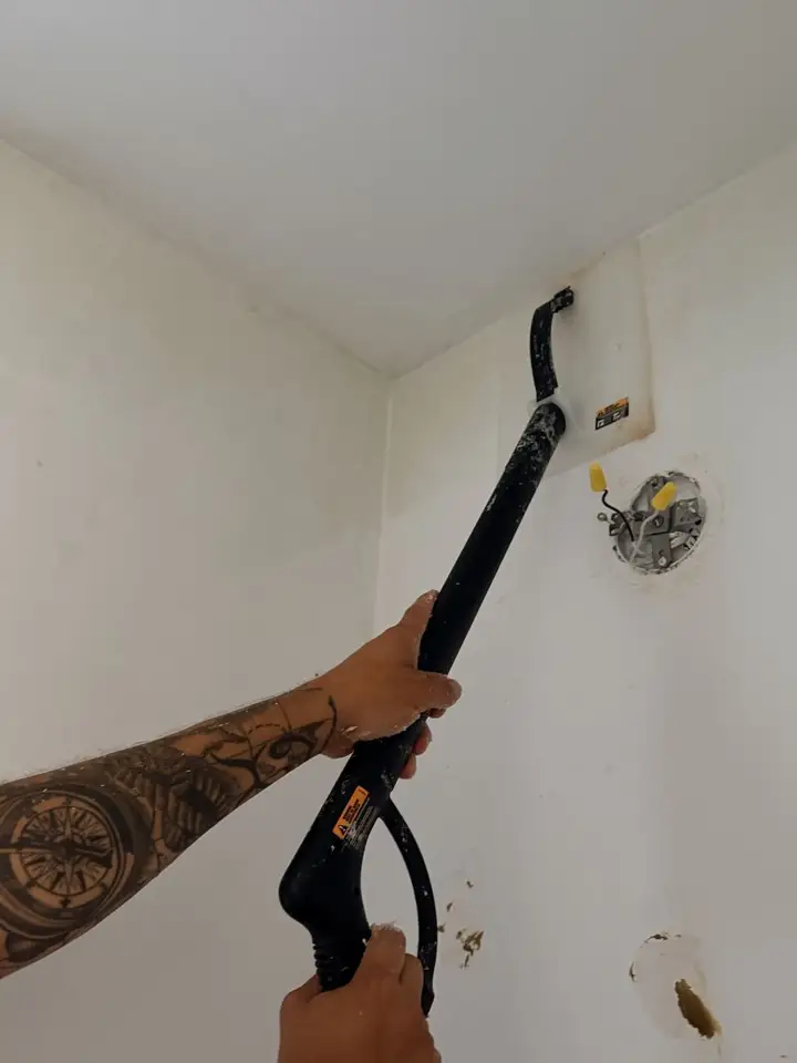 Steamer removing wallpaper from a bedroom wall