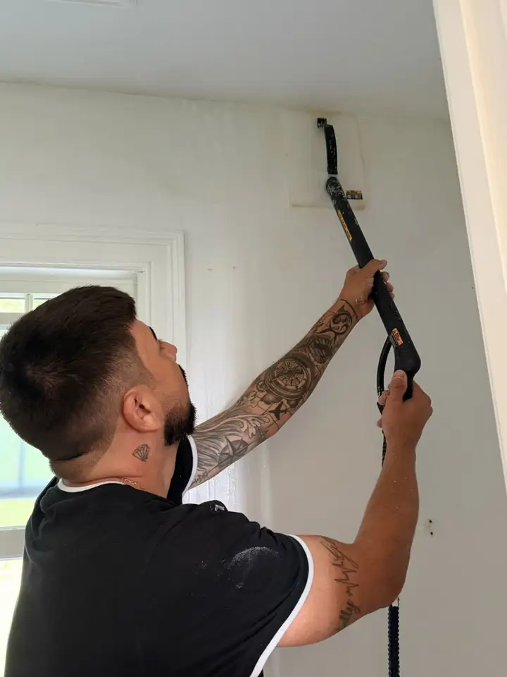 Crew member steaming wallpaper off a wall